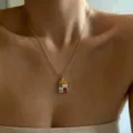 Close-up view of the delicate hand-painted house pendant necklace on collarbone, gold chain. - Playful House Charms