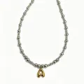Stainless steel round bead necklace gold bubble letter jewelry close up detail view. - Letter A