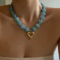 Close-up of the stylish blue marbled heart beaded necklace with a golden hollow pendant detail. - Blue
