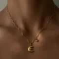 Detailaufnahme der vergoldeten Edelstahl Wellenkette mit dem Buchstaben E Anhänger. - Buchstabe E