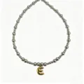Detailed shot of trendy stainless steel beaded necklace with gold bubble letter E pendant. - Letter E