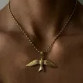 Gros plan élégant du collier pendentif oiseau doré montrant des détails de plumes fins. - Or