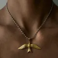Detail de gros plan du magnifique collier pendentif oiseau volant avec chaine metallique. - Bicolore