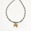 Detailed close-up view of the stainless steel beaded necklace with a golden letter pendant. - Letter M