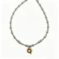 Close-up detail shot of the silver bead necklace featuring a glossy gold bubble letter pendant. - Letter Q