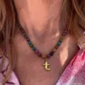 Detailed close-up view of the colorful beaded necklace featuring a glossy gold letter pendant. - Letter T