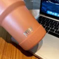 Gedetailleerde close-up van roestvrijstalen beker met siliconen beschermhoes op tafel. - Diameter 71-75mm / Zonnig Oranje