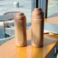 Detailed shot of two portable brown water bottles placed neatly on wooden table near window. - Coffee