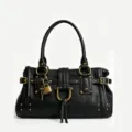Détail de sac à main rétro en cuir noir avec cadenas et rivets métalliques dorés. - Noir