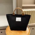 Detail view of small black canvas handbag, Japanese style portable bento bag with brown handles. - Patch Bear / Black