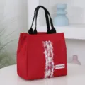 Red canvas lunch bag tote with black handles and fashion tag for daily commute and storage. - Red