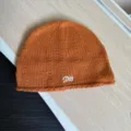 Nahaufnahme einer stylischen orangefarbenen Strickmütze mit weißer Stickerei für den Winter. - M (56-59cm) / Orange