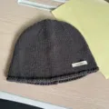 Nahaufnahme Detail einer dunkelgrauen Strickmütze mit kleinem Stoffetikett, weich. - M (56-58cm) / Grau