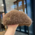 Braune flauschige Wollbarette Detailansicht mit weicher Textur und schickem Lederemblem. - Einheitsgröße (56-58cm) / Kaffee