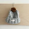 Vue détail bonnet en tricot gris pour enfant avec pompon marron et revers chaud hiver - Taille Unique (50-52cm) / Gris