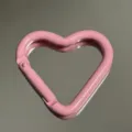 Close-up detail of a pink heart-shaped metal carabiner keychain accessory showing smooth paint. - Heart Buckle / Pink