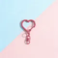 Close-up detail of a pink heart-shaped metal keychain charm and lobster clasp accessory. - Heart Buckle + Figure-8 Buckle / Rose Red