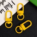 Detail view of yellow zinc alloy swivel snap hooks, keychain hardware and DIY bag accessories. - Yellow