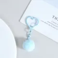 Vue détaillée du porte-clés pompon pelucheux bleu clair avec un charmant fermoir métallique en cœur. - Bleu