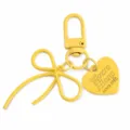 Gele metalen strik vorm sleutelhanger met hartvormige label hanger voor tas decoratie. - Lichtgeel
