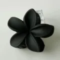 Primo piano di un fermaglio per capelli a fiore di frangipani nero opaco con dettagli. - Nero