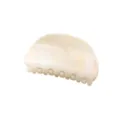 Primo piano del fermaglio per capelli ad arco minimalista in marmo crema per styling chic. - Bianco