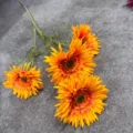 Detailed view of 4-head artificial gerbera daisy flowers with vivid orange petals. - Orange