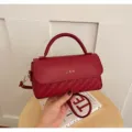 Detailed view of the dark red woven texture women's handbag with top handle and strap. - Red