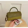 Detailed view of the olive green woven leather crossbody bag with top handle and metal clasp. - Green