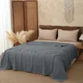 Detailed view of a solid dark grey pure cotton gauze blanket in a cozy bedroom scene. - 110*110cm / Gray