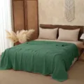 Detail shot of the solid green cotton gauze blanket displayed neatly on a cozy bed, soft texture. - 110*110cm / Green