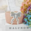 Detailed view of the sparkly rhinestone bow decoration on a colorful silicone cup sleeve accessory. - Pink