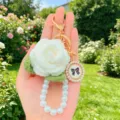 Handgefertigter weißer Häkelrosen-Schlüsselanhänger mit Perlentaschenkette und Vintage-Schleifen-Charm. - Etikett-Stil 2