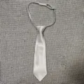 Detail shot of a white pre-tied children tie made of satin fabric with adjustable elastic band. - 28cm / White
