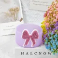 Close-up detail of purple silicone cup boot featuring a sparkly pink rhinestone bow decor. - Purple