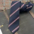 Detail view of a dark blue classic striped polyester tie for men formal business wear. - Hand-Tied Necktie / 145x7cm