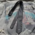 Dark punk style black necktie featuring metal eyelet details and number print close up. - Hand-Tied 3-Hole Style / Black