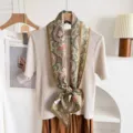 Close-up of green silk wool blend paisley ribbon scarf styled on knit top. Elegant detail. - Green Background Large Paisley