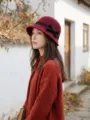 Red wool cloche hat detail showcasing elegant black bow accent and classic retro design style. - Burgundy