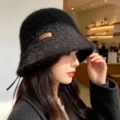 Detail view of the black knit bucket hat featuring side leather tag and warm texture. - One Size / Black With Handmade Label