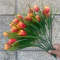 Artificial tulip bouquet detail showing orange flowers and green leaves for decoration. - Orange