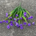 Close-up detail of artificial purple flower bouquet with green leaves for decoration. - Purple