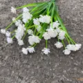 Detailed close-up view of white artificial plastic flower bouquet with green stems for decor. - White
