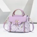 Detailed view of the purple handbag featuring metal swan clasp, top handle, and grid pattern. - Plaid Purple