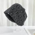 Detailaufnahme der schwarzen Strick-Boonie-Mütze mit weißem Blumenmuster auf Ständer. - Einheitsgröße / Schwarz