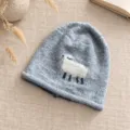 Detailaufnahme einer süßen hellblauen Strickmütze mit niedlichem weißen Schafmotiv, gemütlich. - Einheitsgröße / Grau