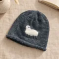 Detailansicht einer dunkelgrauen Strickmuetze mit einem suessen weissen Schaf-Motiv im Winter. - Einheitsgröße / Dunkelgrau