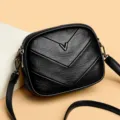 Bolso de hombro negro de cuero sintético con costuras de chevrón y detalle de metal en V. - Estilo Acolchado en V / Negro