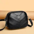 Bolso cruzado negro de cuero con costuras acolchadas y elegantes detalles de metal. - Estilo Cerradura Trébol / Negro