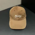 Close-up of the brown corduroy baseball cap with front embroidered lettering and fine stitching. - Adjustable / Coffee